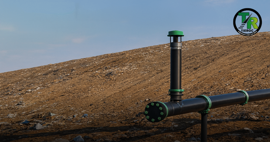 Studnia i rurociąg do gromadzenia gazu składowiskowego na zboczu składowiska odpadów pod błękitnym niebem, z logo TIEROC w prawym górnym rogu.